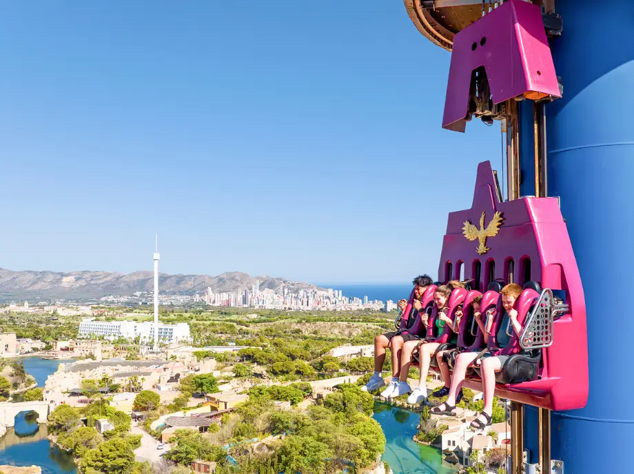 Atracción de caída libre en Terra Mítica Benidorm con visitantes suspendidos en altura.
