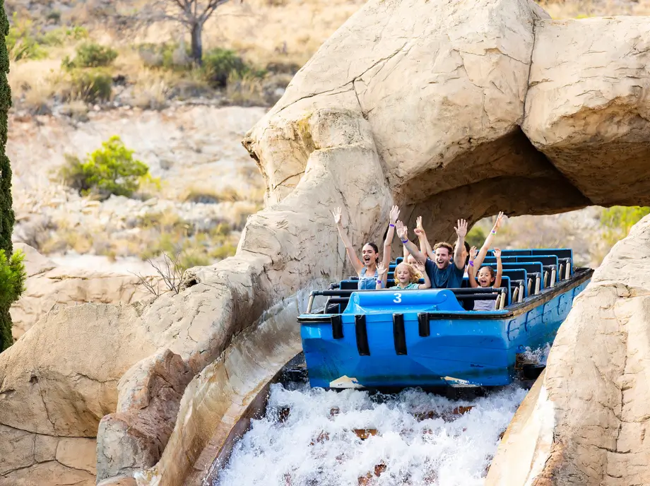 Atracción acuática de Terra Mítica en Benidorm con barca azul descendiendo entre rocas.