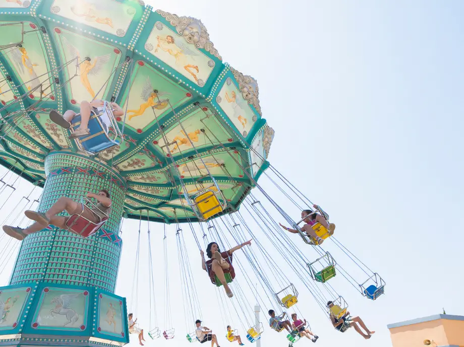 Atracción de sillas voladoras en Terra Mítica Benidorm con visitantes girando en el aire.