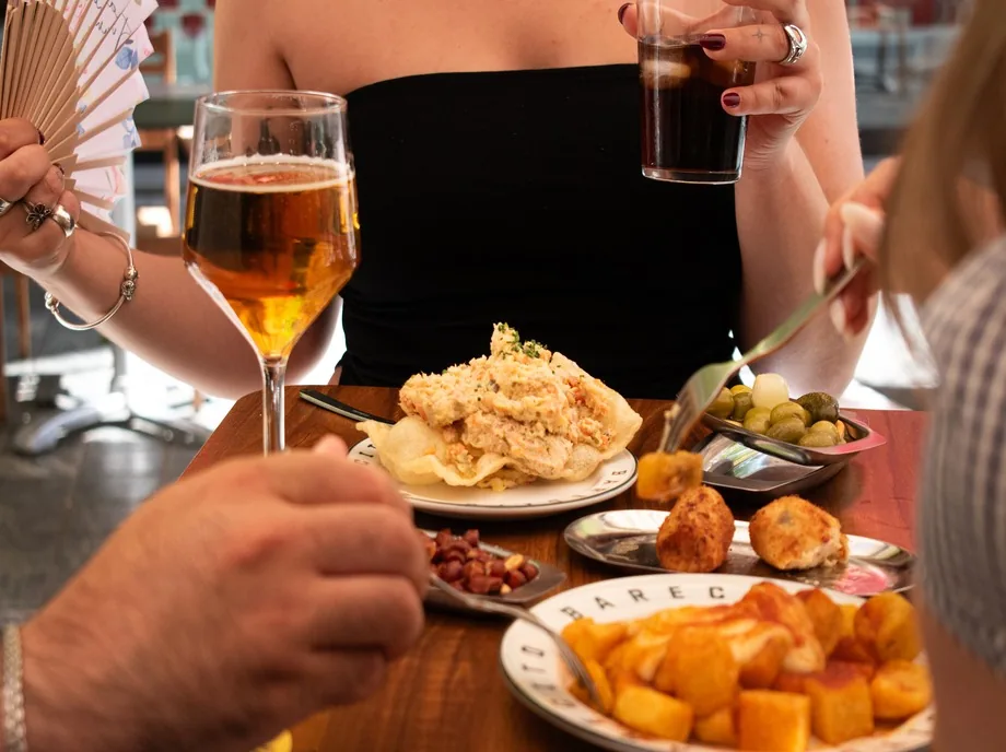 Mesa con ensaladilla rusa, croquetas, patatas bravas y bebidas en Barecito Valencia