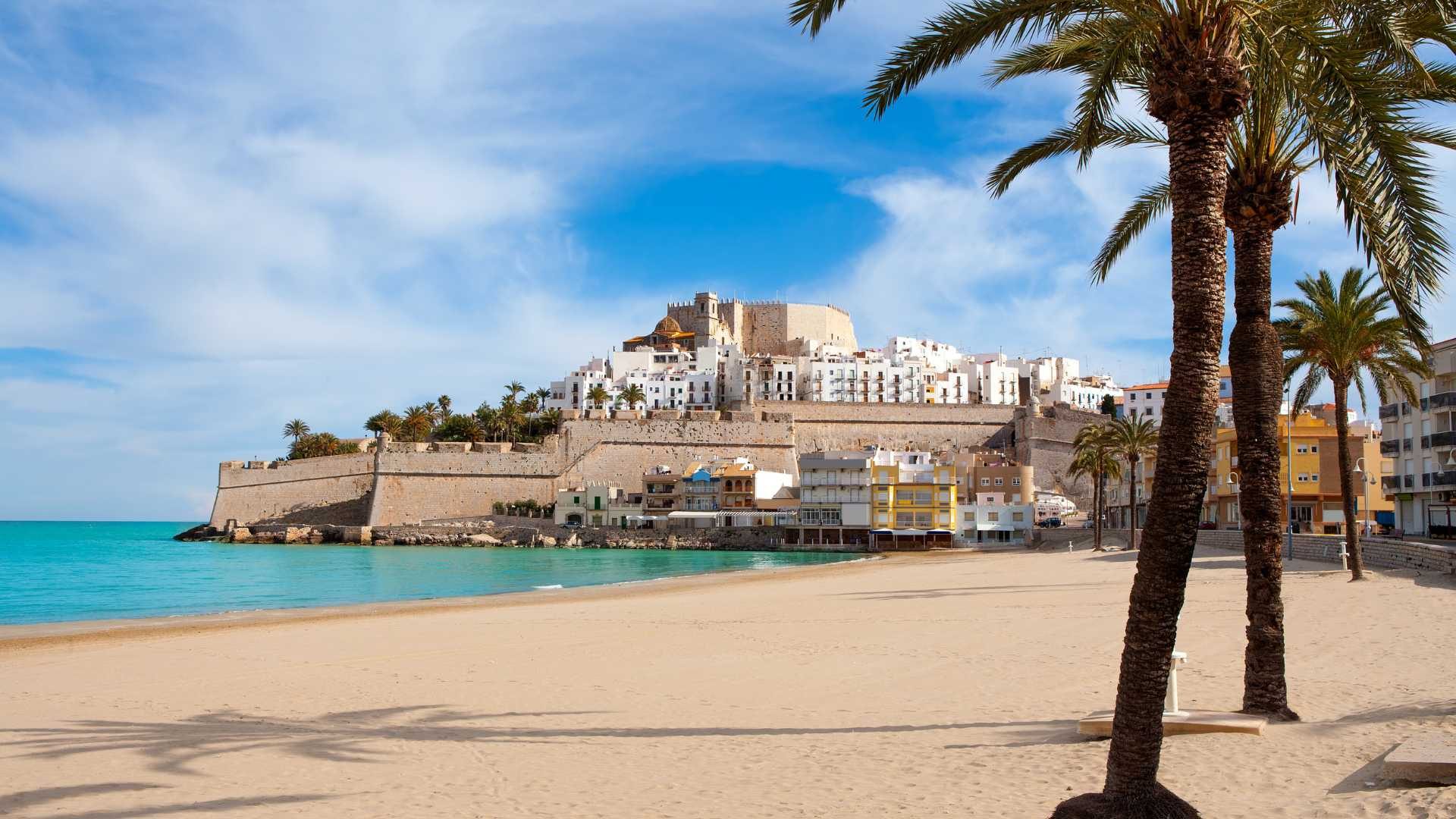 Playa de Peñíscola con palmeras y el castillo al fondo