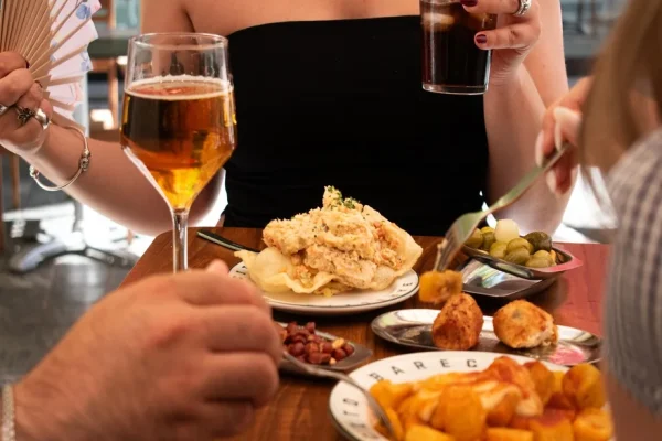 Mesa con ensaladilla rusa, croquetas, patatas bravas y bebidas en Barecito Valencia