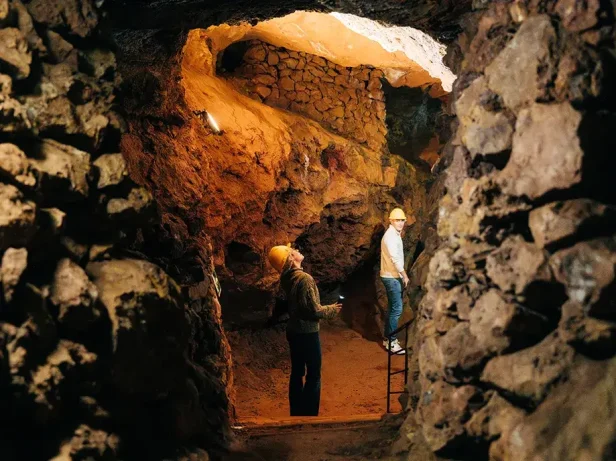 Helmeted visitors touring a rock gallery in the Parc Miner del Maestrat